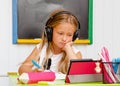 Causacian cute school kid with earphones is on boring online home education. Distance learning