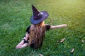 Causcasian blond girl with long hair in halloween witch costume sitting on a grass Royalty Free Stock Photo