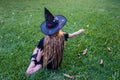Causcasian blond girl with long hair in halloween witch costume sitting on a grass Royalty Free Stock Photo