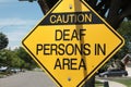 caution deaf persons in area diamond sign in black writing on yellow background