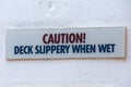 Caution Deck Slippery When Wet sign on a white wall Royalty Free Stock Photo