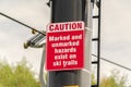 Caution and hazard sign on ski trails and chairlift against blurry trees and sky