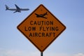 Caution low flying aircraft sign with an aircraft in the background