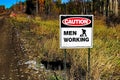 A caution men working sign beside a road