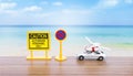 Caution and no entry sign with model car and beach chair and life buoy over blurred beach background