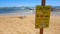 Caution sign with monk seal on beach