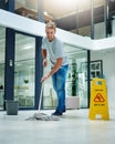 Caution Slippery when wet. a young man mopping the office floor. Royalty Free Stock Photo