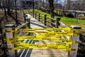 Caution tape blocking wooden walkway bridge on University Campus - metaphor for danger on campus - COVID-DELTA