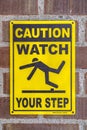 Caution Watch Your Step sign on a brick wall Royalty Free Stock Photo