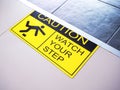 `Caution watch your step` on yellow and black warning sticker sign Royalty Free Stock Photo