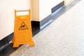 Caution wet floor orange fold out sign without text in a bright corridor, closeup detail Slipping man symbol, object up close