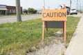 caution word caption text sandwich board wooden sign next to sidewalk and grass. p
