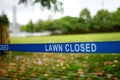 Cautions tape with writing `Lawn closed` means, that access on lawn forbidden. Royalty Free Stock Photo