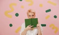 Cautious young woman with short blond hair covering her mouth with a book Royalty Free Stock Photo