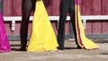 Cavaleiro in grey suit stand on arena holding bright rags