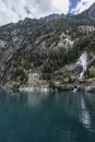 Cavallers reservoir between high mountains, a waterfall and a building of the hydroelectric power station, river Noguera de Tor in