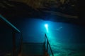 Cave divers training deep cave dives in old coal mine lake. Light from cold blue water.