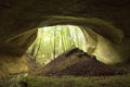 Cave entrance in huge cliff in the forest with man standing in front Royalty Free Stock Photo