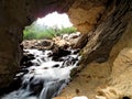 Entrance of a Cave River with a small waterfall into an underground cave Royalty Free Stock Photo