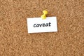 Caveat. Word written on a piece of paper, cork board background