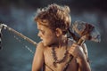 Caveman, manly boy with primitive weapon hunting outdoors. Ancient prehistoric warrior. Heroic movie look Royalty Free Stock Photo