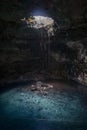 Cavern cenote Samula with turquoise water lagoon and jungle roots growing in from upper hole near Valladolid, Yucatan, Mexico