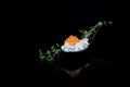 Caviar Seafood Appetizer garnished with green leaves, one spoon isolated on black background with reflections