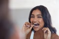 Those cavities dont stand a chance. an attractive young woman flossing her teeth in the bathroom at home. Royalty Free Stock Photo