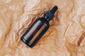 CBD oil bottle, hyaluronic acid tincture on creased cardboard. Serum with collagen and peptides on wrinkled crumpled