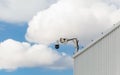 CCD surveillance camera mounted on a hangar in front of a cloudy blue sky