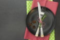 cChristmas place setting with ribbon. Black plate with fork and knife, decorated. Top view, copy space