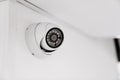 CCTV camera with broken glass on a white wall under the ceiling.