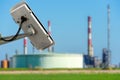 CCTV camera concept with fuzzy oil storage tanks on background