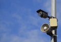 CCTV camera and loudspeaker alarm on a pole against a blue sky. Royalty Free Stock Photo