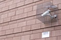 CCTV security camera in operation in cage fixed to wall of workplace office block in city to reduce crime