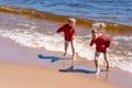 Ccute caucasian boys wearing red hoodies and blue underpants running from waves Royalty Free Stock Photo