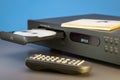 CD player, open disc tray, remote control on the table. Close-up, blue background.