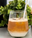 Ced coffee in a short glass with cream poured over iced cubes on a wood table near the window in the living room. Cold drink help Royalty Free Stock Photo