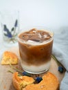 Ced coffee in a short glass with cream poured over iced cubes on a wood table near the window in the living room. Cold drink help Royalty Free Stock Photo
