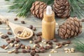 Cedar essential oil bottle, whole and shelled nuts on bamboo spoon, pine cones and green needle branches on wooden table. Cedar Royalty Free Stock Photo