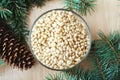 Cedar pine nuts in glass bowl with cones, cedar brunch on wooden background. Top view Royalty Free Stock Photo