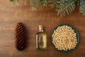 Cedar products: cedar oil in glass bottle, pine nuts, cone, brunches on a wooden broun background. Top view Royalty Free Stock Photo