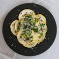 Cedri slices, a citrus fruit, with rucola, red berries, grated parmesan cheese on a black plate