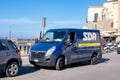 Blue Opel Movano EcoFlex post office van of the SDA Posta Italiane delivering the parcels and packages near the beach in Cefalu,