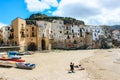 Cefalu, Sicily, Italy - Apr 7, 2019: Mother with children playing on a sandy beach in a small Sicilian village. Beautiful old Royalty Free Stock Photo