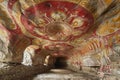 The ceiling of the cave is decorated with red and yellow images, including bison figures, abstract shapes, and patterns that