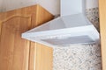 Ceiling metal white cooker hood above the kitchen stove. Modern kitchen appliances