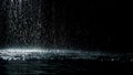 From the ceiling spatters rain fall against on the water surface which glow. Black background. White neon lighting in