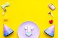 Celebrate birthday of a little baby. Cookies in shape of accesssories for child and party hats on yellow background top