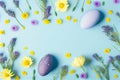 Easter eggs with purple and yellow flowers on pastel Spring blue background Royalty Free Stock Photo